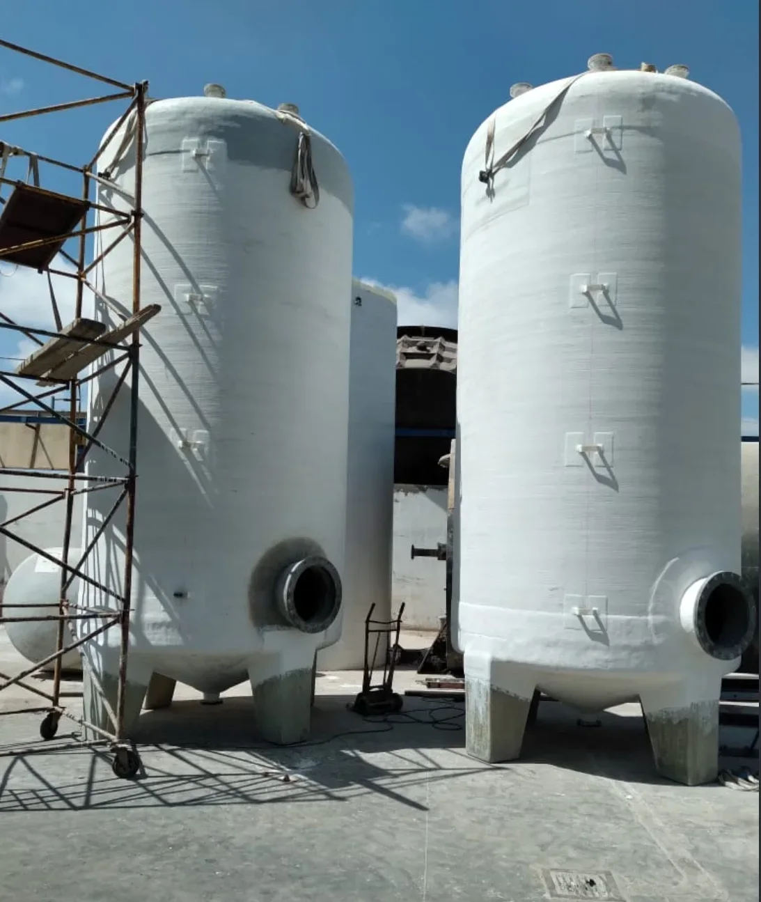 Réservoirs cylindriques verticaux en PRV sur pieds, avec piquages.