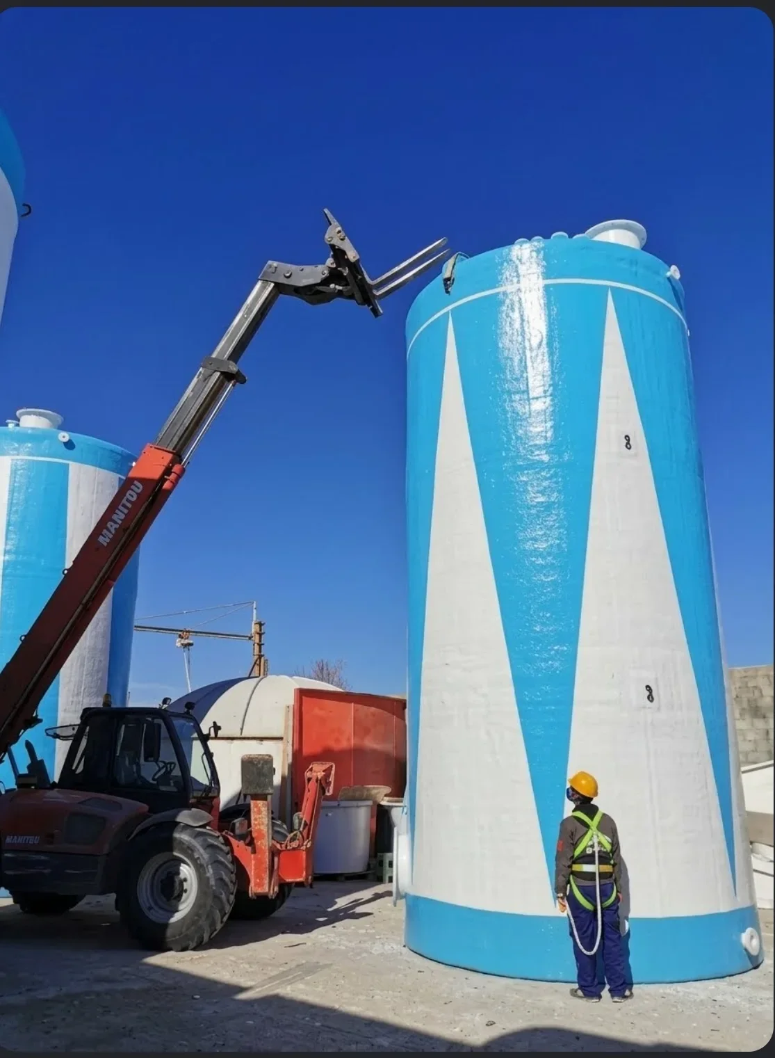 Grand réservoir vertical en PRV, mise en place avec engin de levage.